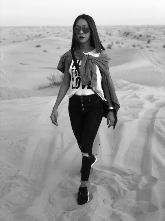 a woman walking in the sand in sunglasses