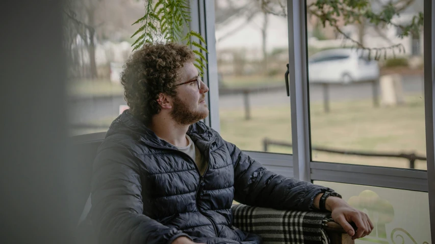 a man sitting on a couch looking out a window