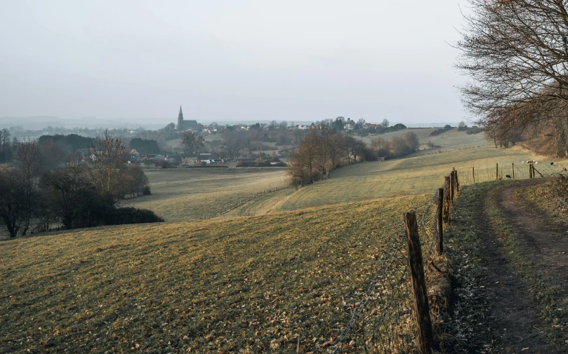 an open field has a fence and a town on the horizon