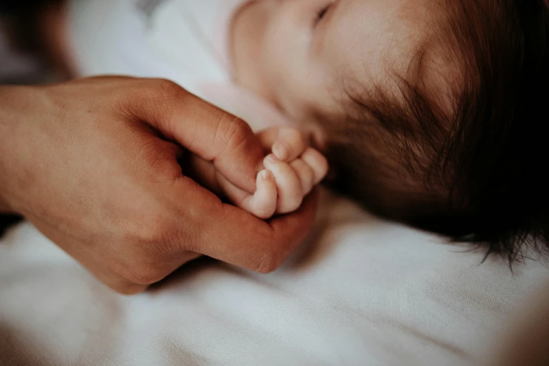 a man laying in bed while holding a sleeping baby