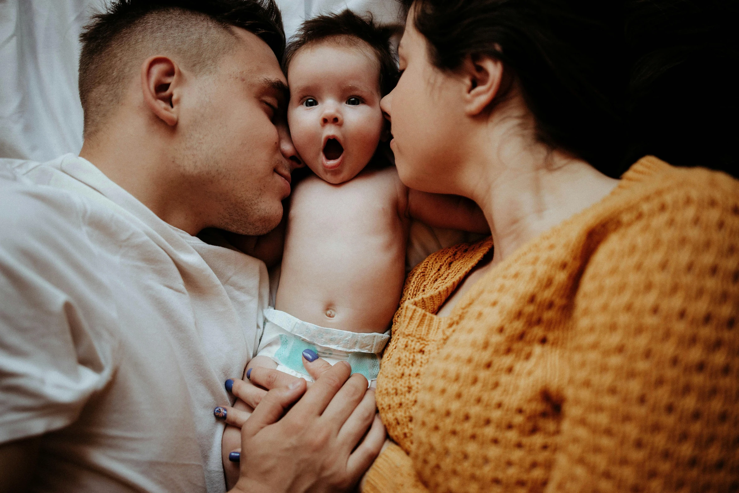 a young adult holds a crying baby with the head of an older adult