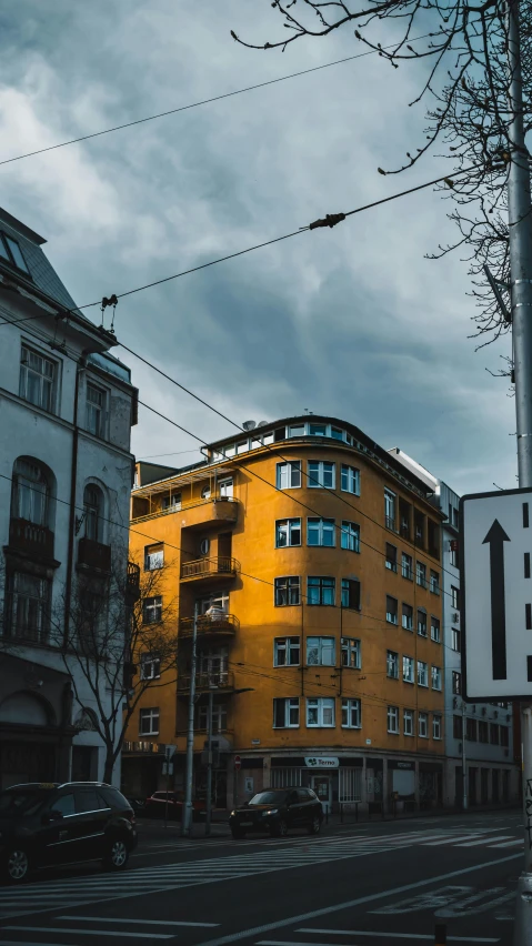 a yellow building sitting next to a tree in a city