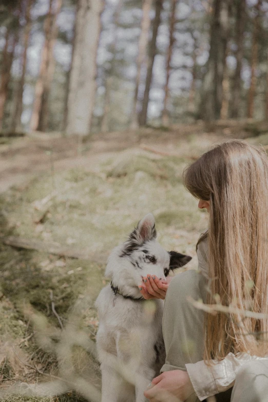 a woman kneeling down and holding her dog in front of her