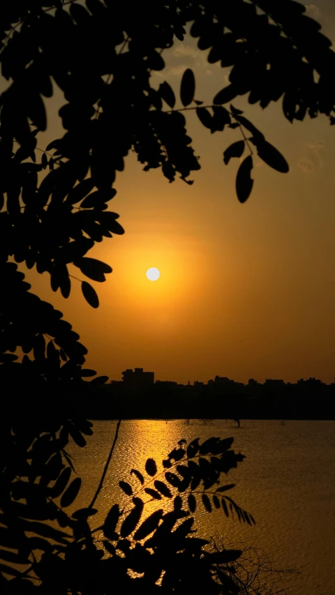 the sun rising behind a building in front of a lake