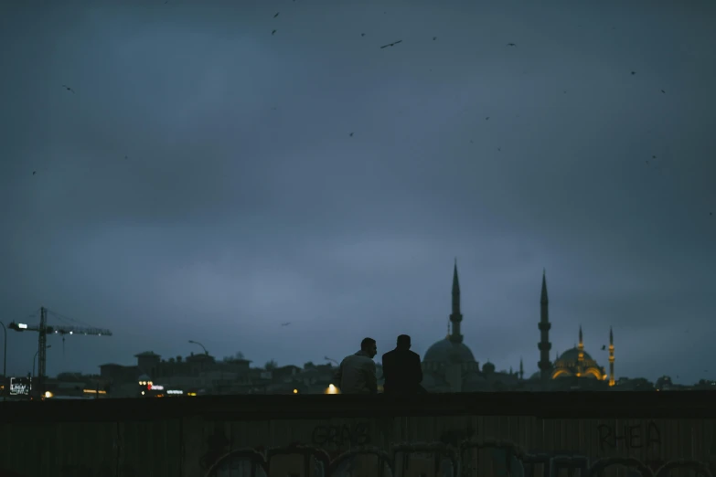 silhouettes stand against the evening sky on a balcony