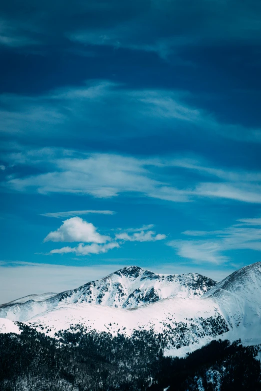 a snowy mountain is seen with some clouds in the sky