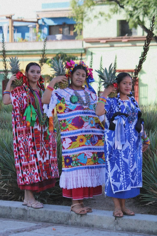 three woman in a native fashion stand on concrete