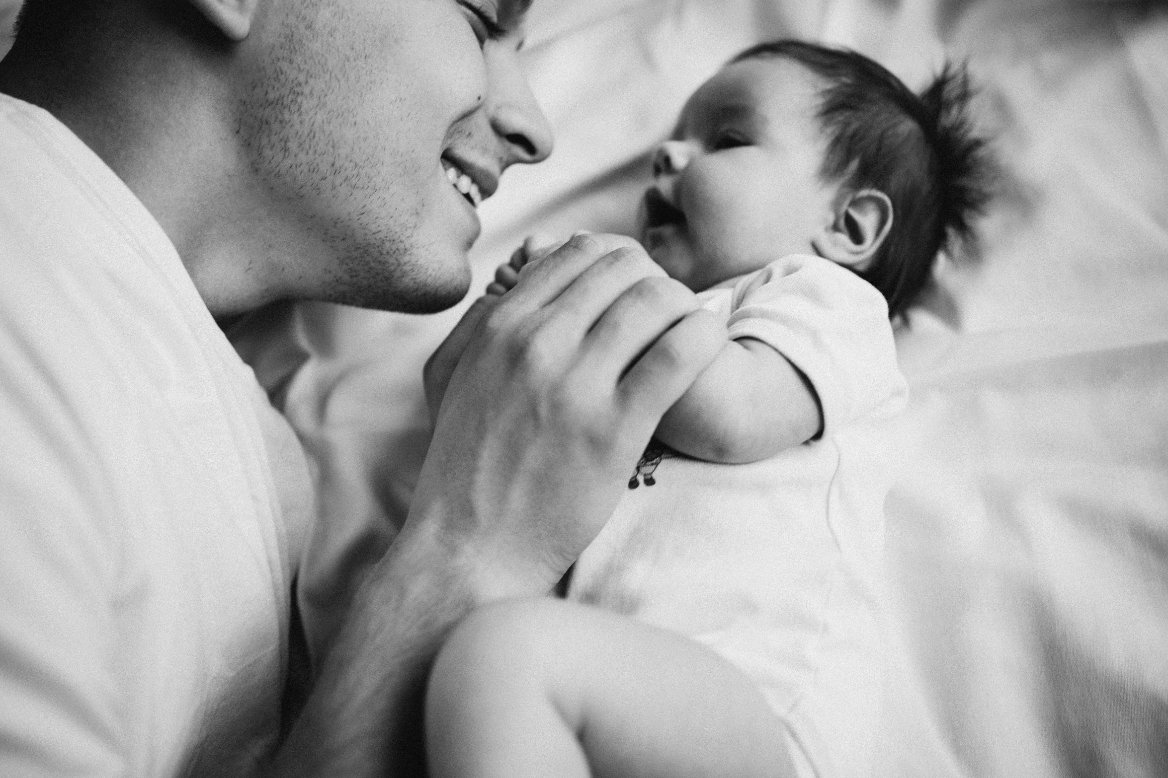 man holding a baby, his face close to his face