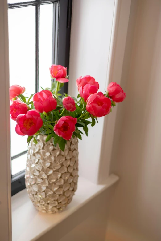 a vase filled with red tulips on a window sill