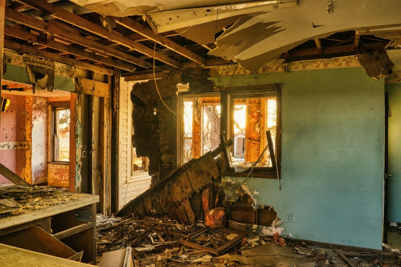 an unfurnished room with peeling paint, windows and debris on the floor