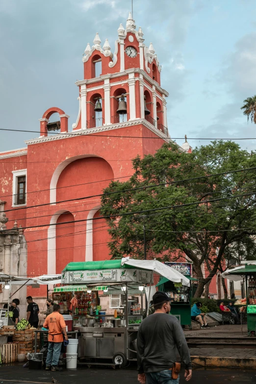 a man is looking at an outdoor market near a big red building