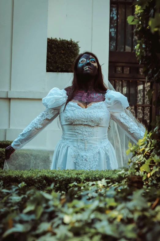 a woman standing on a lush green lawn wearing a wedding dress