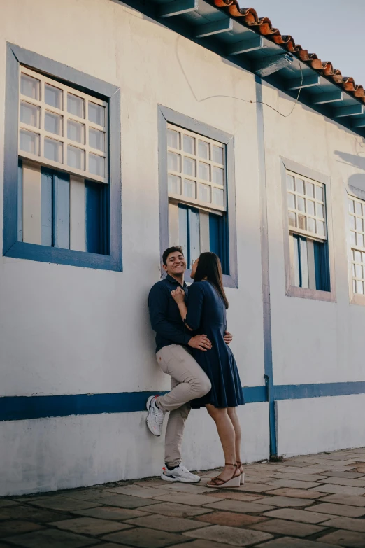 a man and woman leaning against the side of a building