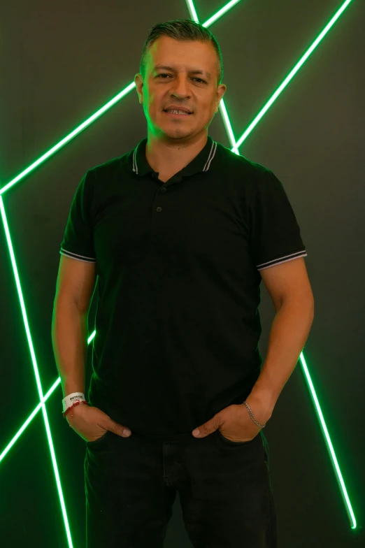 a man standing next to a green wall with neon lines on it