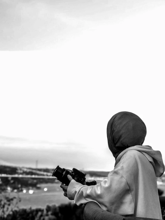 a person standing by some hills with a camera in his hand