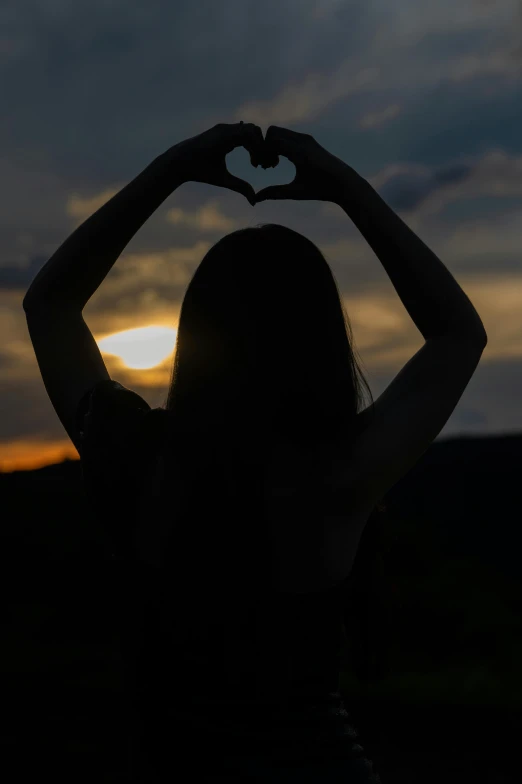 silhouette of a girl with her hands in the shape of a heart