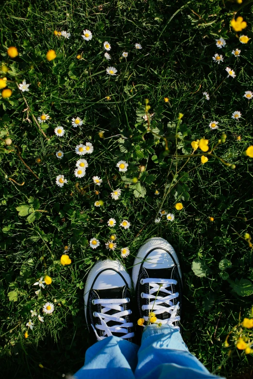 a person with their feet up in the grass by flowers