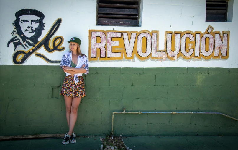 a young woman standing in front of a wall that says revolution