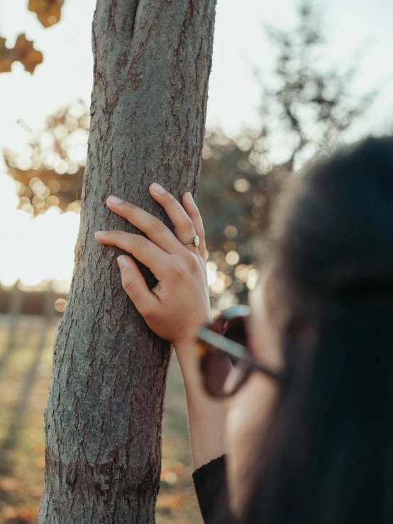 a woman who is holding a ring to a tree