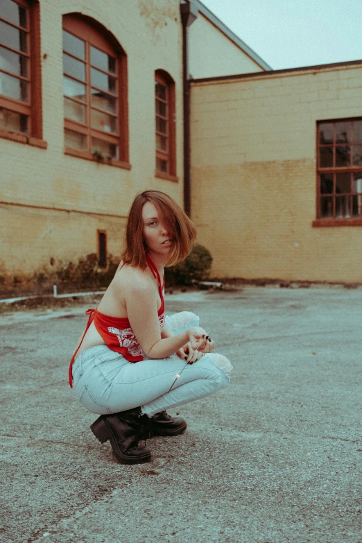 the girl is sitting on the ground near a building