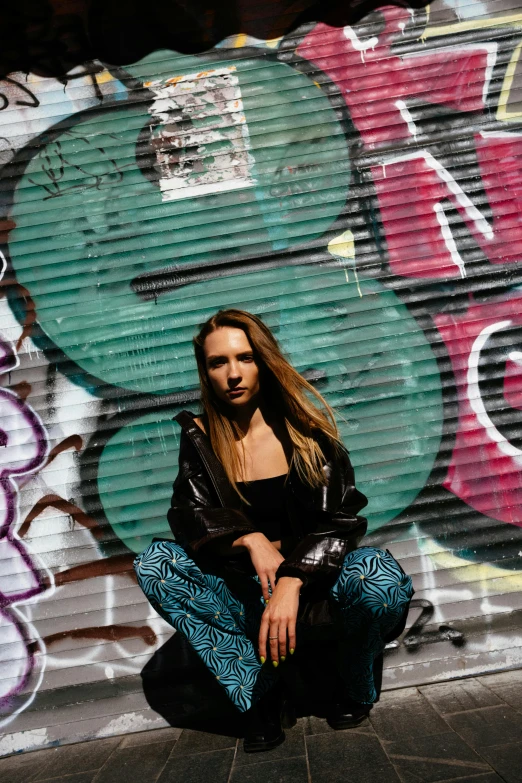a woman squats down in front of colorful grafitti