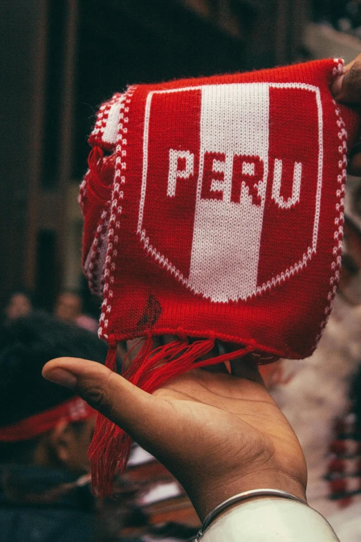 a person holding up a red purse with the word peru written on it