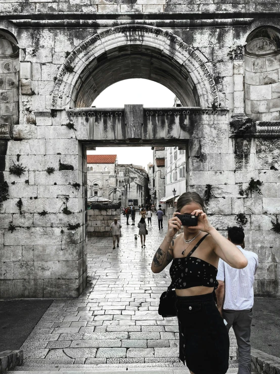 a woman standing in front of a gate while looking at her phone