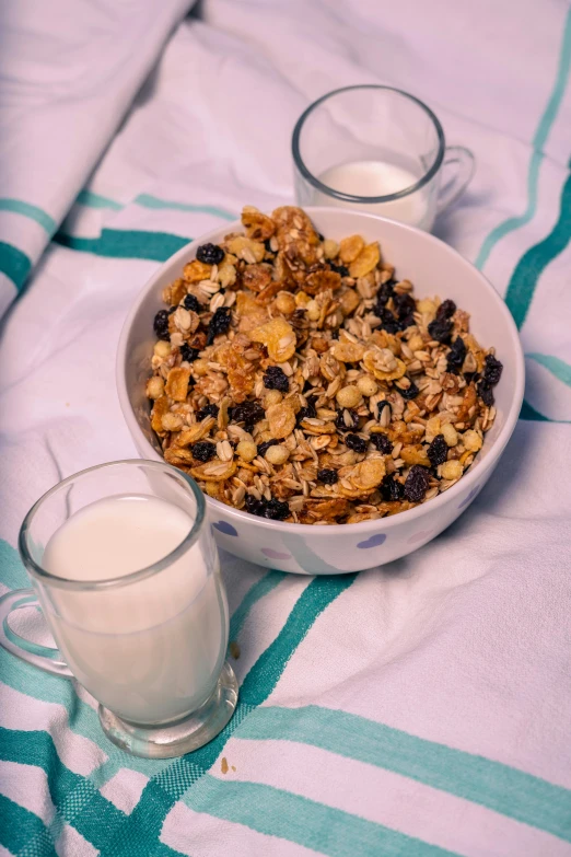 a bowl of oatmeal and a glass of milk on a bed