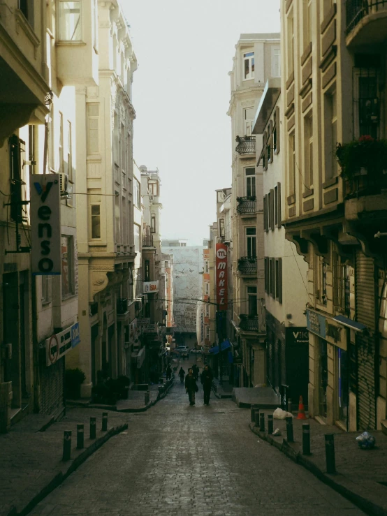 a small group of people walk down the street between old buildings