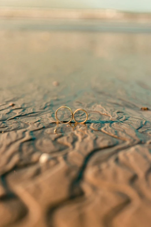 two wedding rings are on the sandy beach