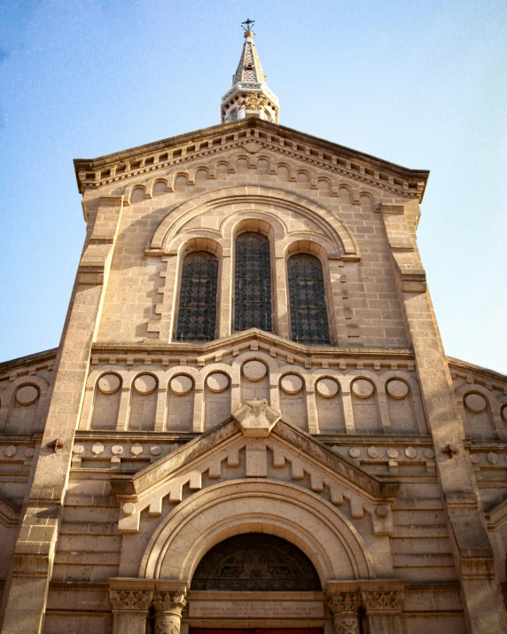 the front view of an old cathedral with a steeple and round windows