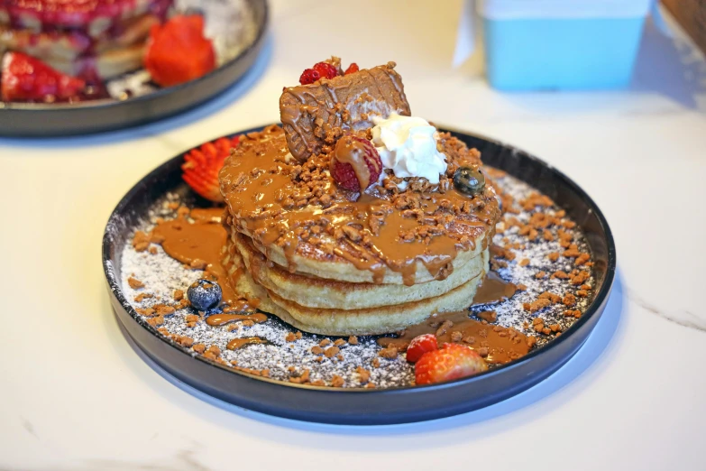 two pancake stacks sitting on top of each other covered in chocolate and fruit