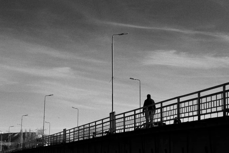 a man walking across a bridge over water