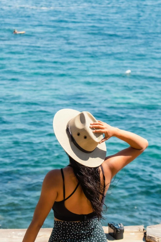 a woman wearing a hat is looking out at the water