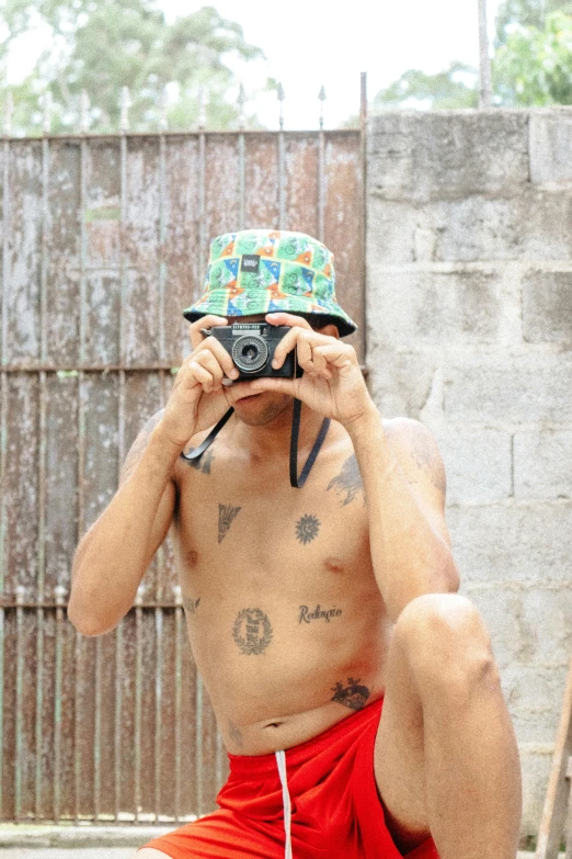 a man with an odd hat covering his face holding a camera