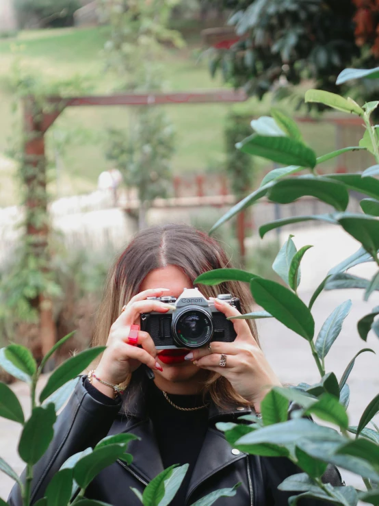 a woman in a black top holding a camera and looking at it