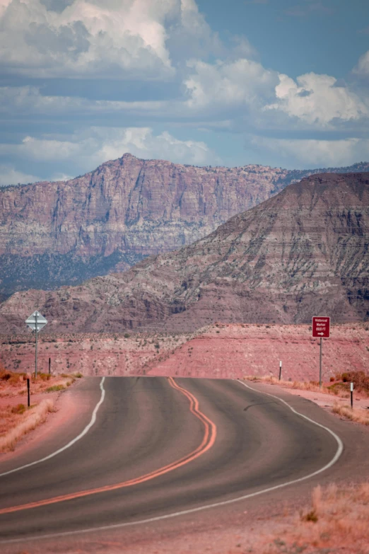 a winding road surrounded by mountains with a sign on it