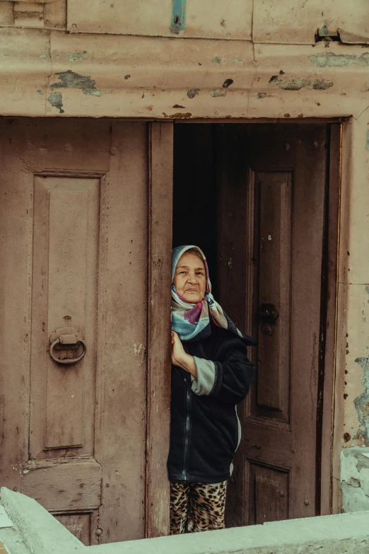 a person standing outside a door with a scarf on