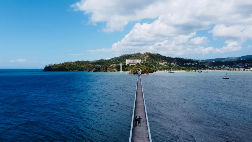 people walking along a pier next to the ocean