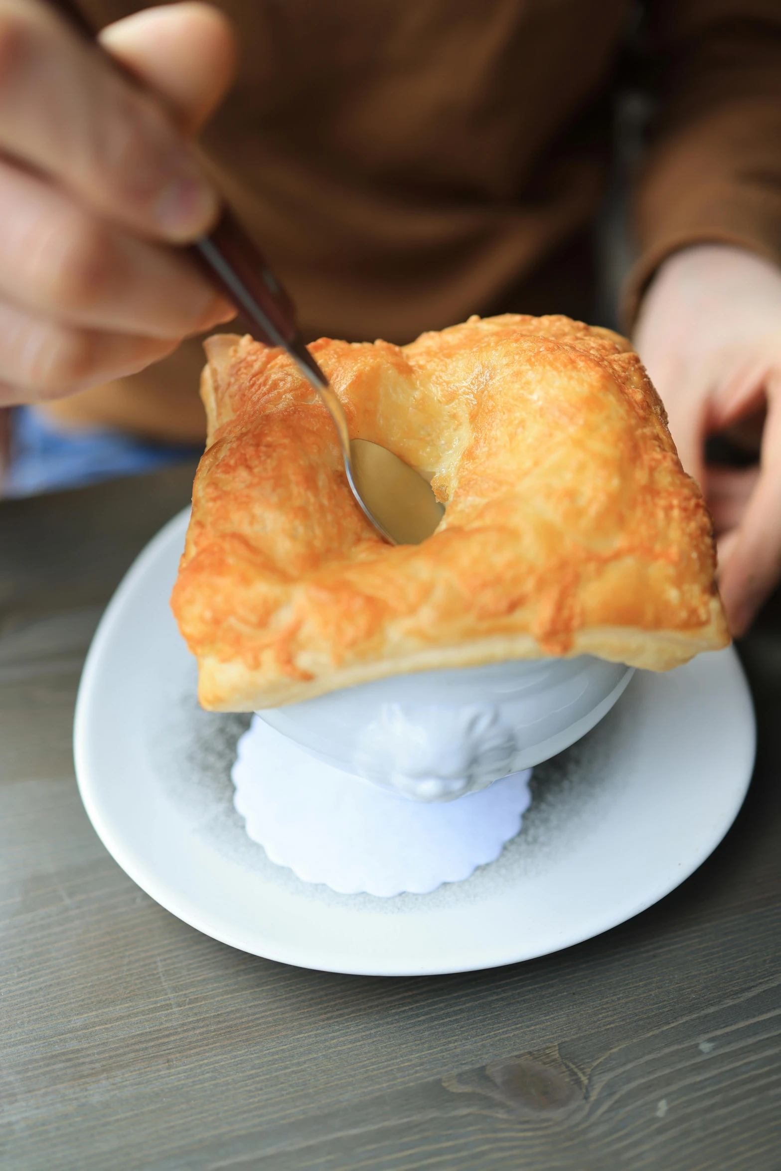 someone using a spoon to cut into a pastry