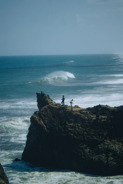 a person on rocks near water with waves in the background