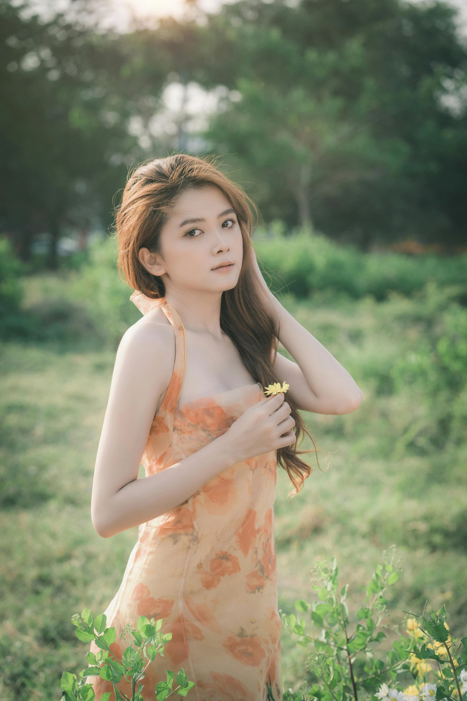 an asian woman in an orange and pink floral print dress, holding a rose