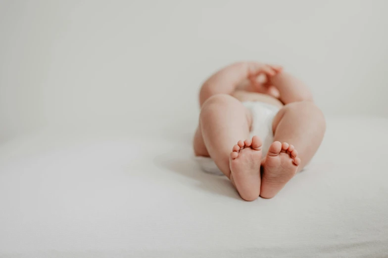 a small baby is laying on the side of a bed