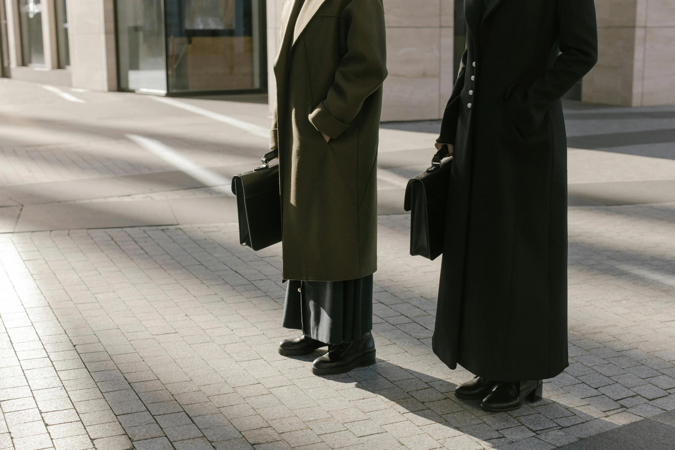 two men standing next to each other on a sidewalk