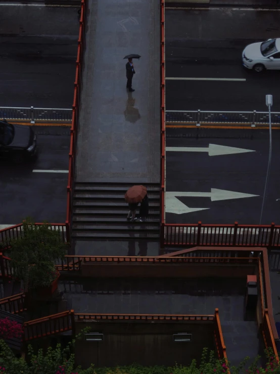 an overhead s of traffic and people under umbrellas on a rainy day