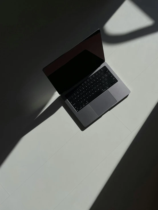 a laptop is opened on the table and shadow is cast on it