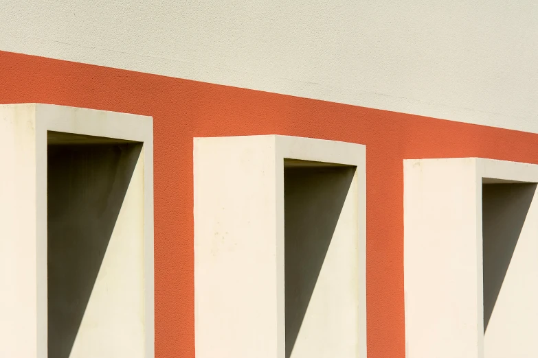 an orange and white wall with three windows and a bird standing on the window sill