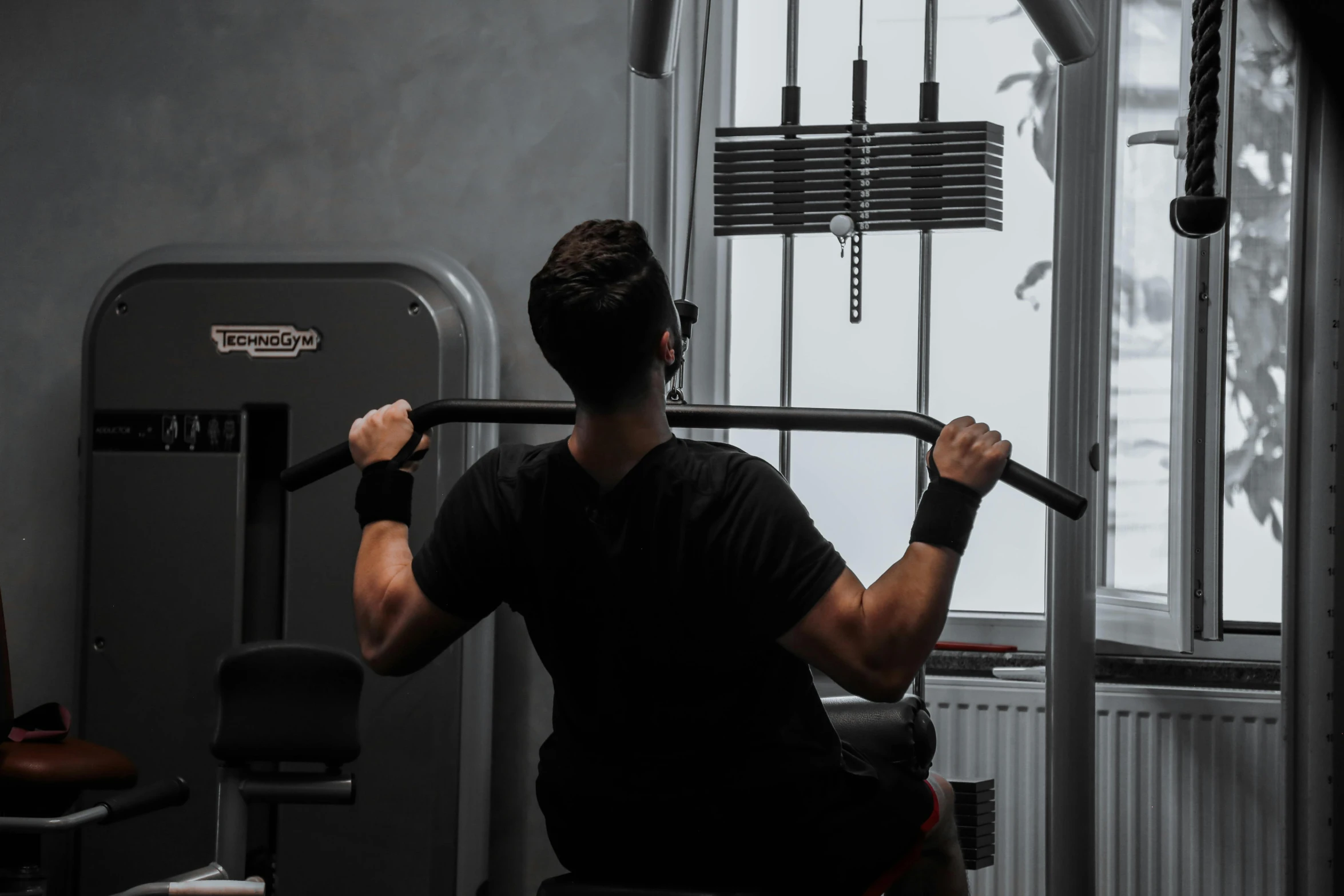 a man holding a gym bar while looking out the window