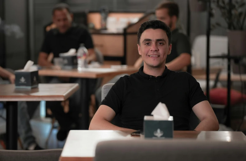 a man is sitting in a restaurant with a smile on his face