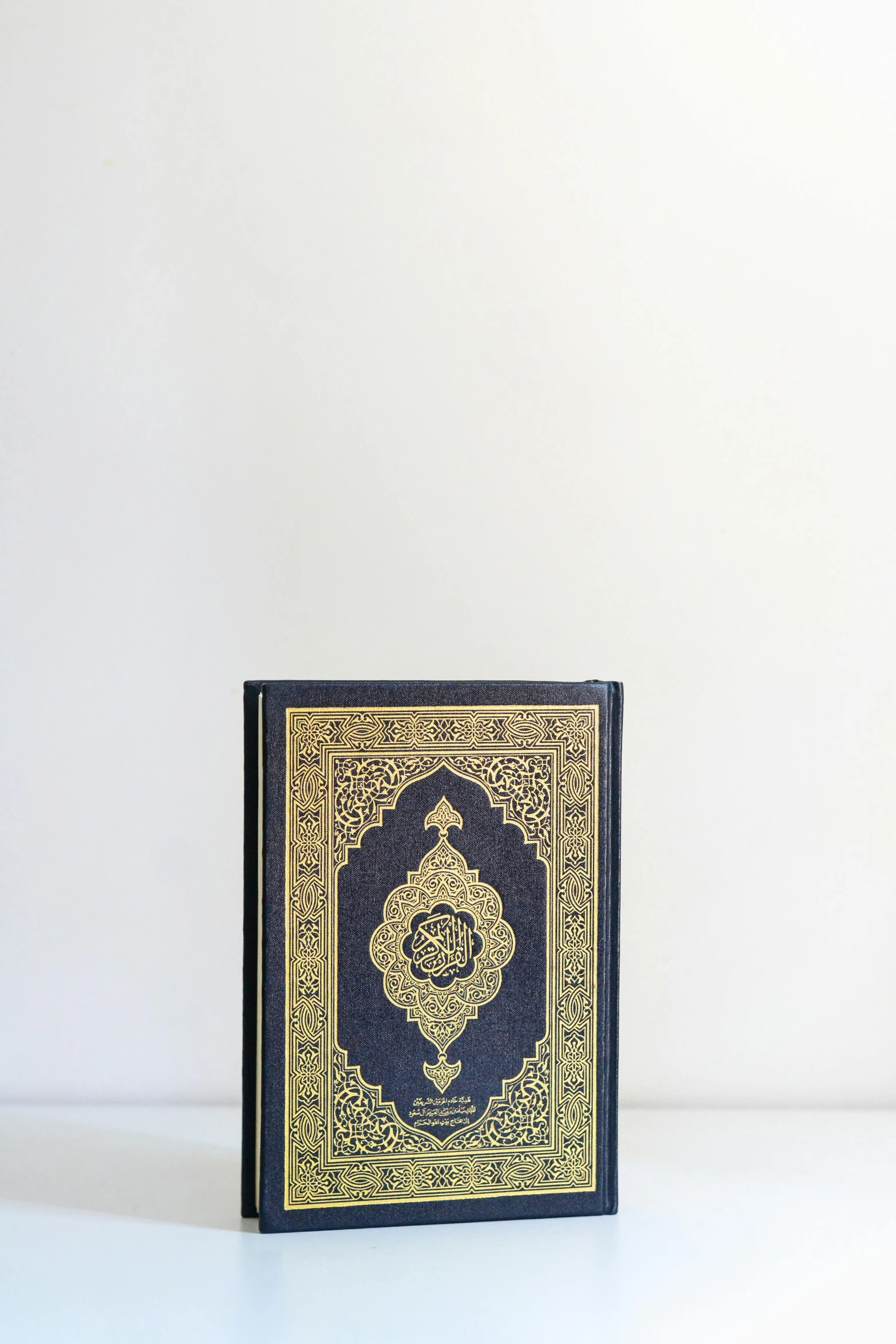 a small black and gold religious book sitting on a table